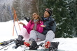 Mixed race couple sitting in snow on ski vacation