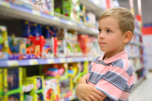 Photo: Boy looks at shelves with toys in shop Boy looks at shelves with toys in shop