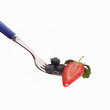 Erdbeere halbiert mit Blaubeeren auf Gabel