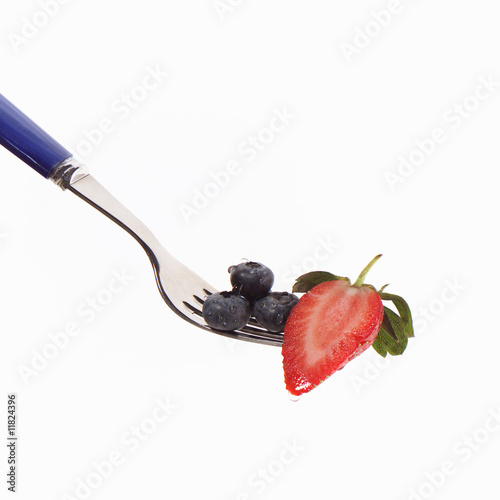 Foto: Erdbeere halbiert mit Blaubeeren auf Gabel Erdbeere halbiert mit Blaubeeren auf Gabel