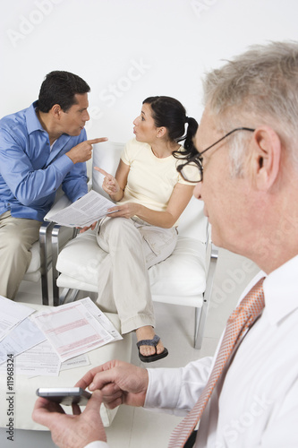 Photo: Businessman Assisting Angry Couple Businessman Assisting Angry Couple