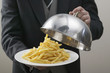 butler lifting serving dome from plate of chips