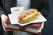 woman holding sandwich and drink on organiser