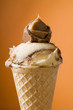 caramel ice cream in wafer cone against orange background