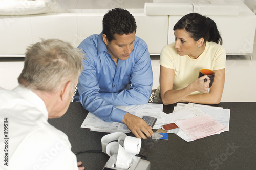 Photo: Businessman Assisting Couple with Credit Cards Businessman Assisting Couple with Credit Cards