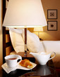 Teapot with a cup of tea on a table in a bedroom.