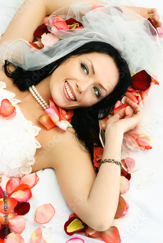 brunette bride on the bed covered with rose leaves