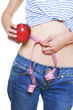 Woman measuring her small waist and holding red apple