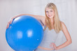 Pretty young blond hair girl holding blue pilates ball