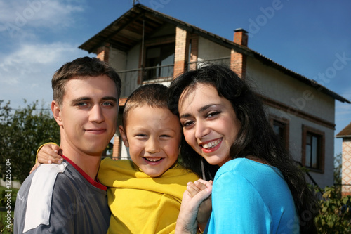 Photo: Young happy family beside their new house Young happy family beside their new house