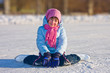 Girl on skates sitting on the ice.