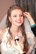 visagiste does a make-up to the bride before wedding