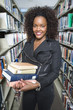 Female University student holding books in library, portrait
