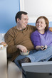 Overweight couple eating on sofa