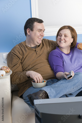 Photo: Overweight couple eating on sofa Overweight couple eating on sofa