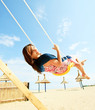 Girl playing on a swing-set on the beach Girl playing on a swing-set on the beach