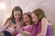 View of three cute girls holding a cellphone.