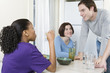 Foto: Two women sitting at the dining table with a man. Two women sitting at the dining table with a man.