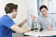 Foto: Two men pointing fingers at each other at the dining table. Two men pointing fingers at each other at the dining table.