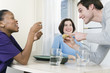 Foto: Man showing muffin to two women at dining table. Man showing muffin to two women at dining table.