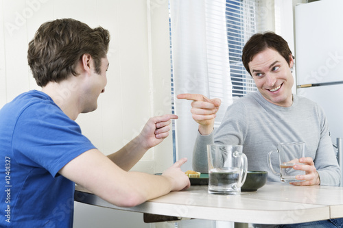 Photo: Two men pointing fingers at each other at the dining table. Two men pointing fingers at each other at the dining table.