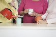 A woman pouring tea into a mug.
