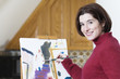Smiling young woman painting on a drawing paper.