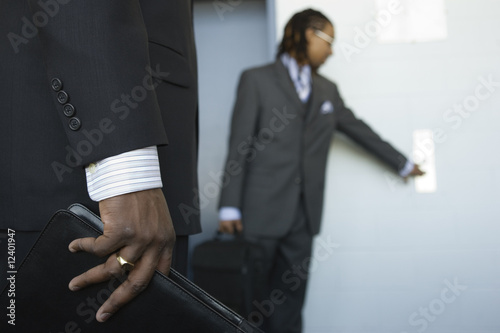 Photo: A young business man pressing push button of an elevator. A young business man pressing push button of an elevator.