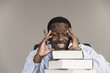 Photo: Tensed business man sitting behind a pile of books. Tensed business man sitting behind a pile of books.
