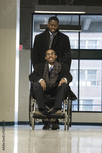 Photo: A businessman helping his colleague in a wheelchair. A businessman helping his colleague in a wheelchair.