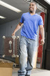 Young man carrying suitcase and smiling.