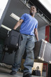 Young man carrying suitcase and smiling.