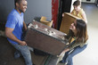 Young man and woman carrying heavy box.