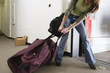 Young woman pulling a huge traveling bag.