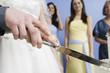 Midsection of a couple cutting cake.
