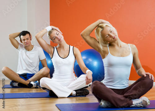Foto: Group of people doing yoga exercise (focus on woman in the middl Group of people doing yoga exercise (focus on woman in the middl