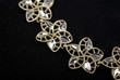 Bracelet made of golden flowers macro isolated on black velvet b