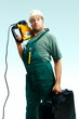 Serious workman hold perforator and suitcase Serious workman hold perforator and suitcase