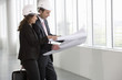 Two architects wearing hard hats looking at plans