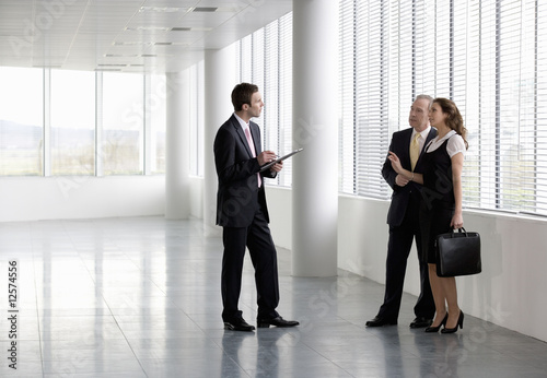 Photo: A letting agent showing businesspeople around an empty office A letting agent showing businesspeople around an empty office