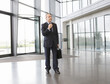 A mature businessman standing in the lobby adjusting his tie