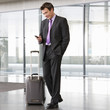 A businessman standing with a suitcase talking on a mobile phone