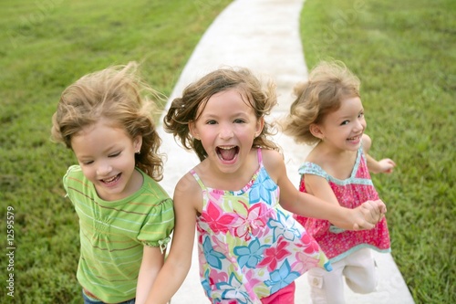Photo: Three sister girls playing running on the park Three sister girls playing running on the park