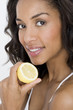 A young woman holding half a lemon