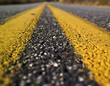 Two yellow lines are seen painted on a tar road