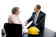 two business partners at desk shaking hands