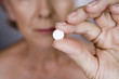 A senior woman holding a pill