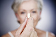 A senior woman holding a pill