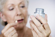 A senior woman holding a bottle of pills