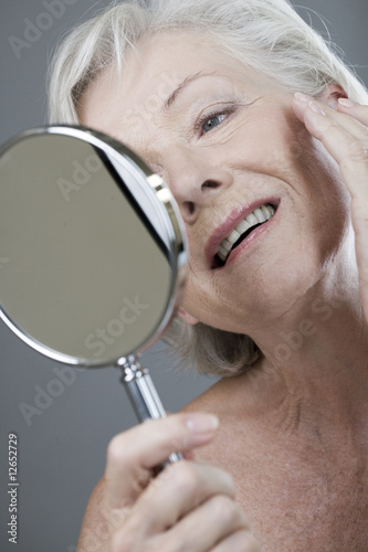 Photo: A senior woman looking at her face in the mirror A senior woman looking at her face in the mirror